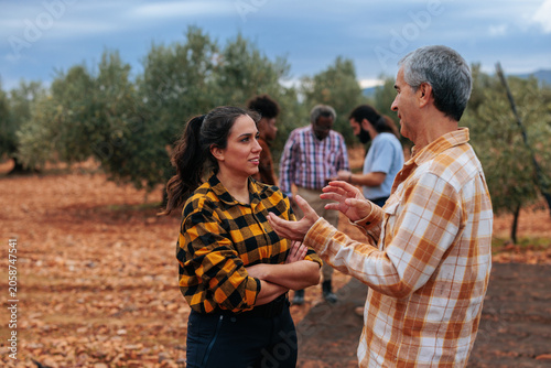 Farmers conversing in olive grove during agriculture community meeting