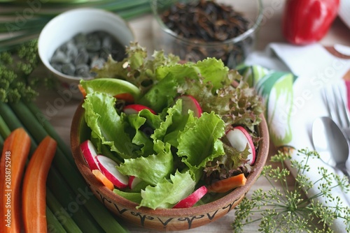 Fresh lettuce of different kinds served in the bowl. Healthy lettuce salad, radish and carrot.
