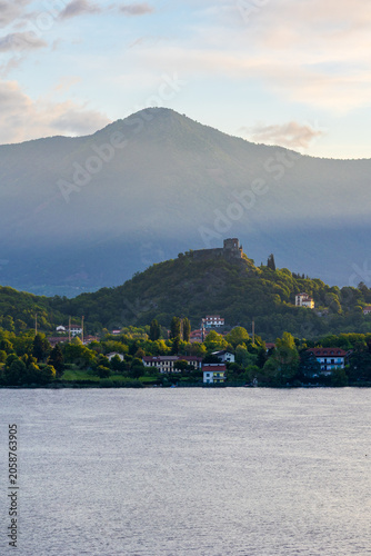 Village of Avigliana dominated by the ruins of its medieval castle at sunrise, seen from the opposite bank of the Lago Grande di Avigliana