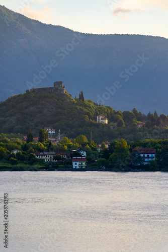 Village of Avigliana dominated by the ruins of its medieval castle at sunrise, seen from the opposite bank of the Lago Grande di Avigliana