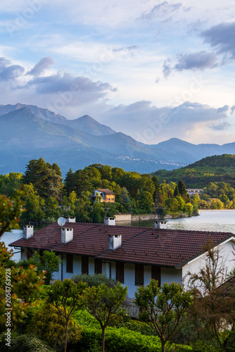 Villas on the shores of the Lago Grande di Avigliana surrounded by Alpine mountains at sunrise, Avigliana Nature Park, Susa Valley