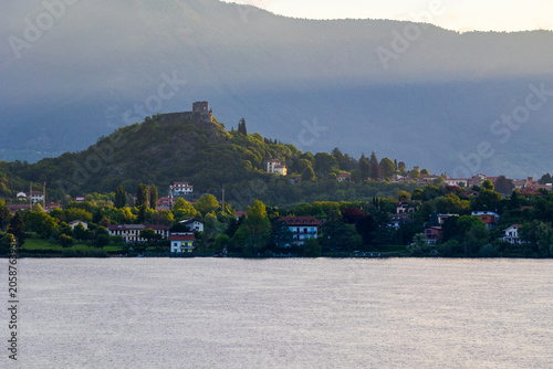 Village of Avigliana dominated by the ruins of its medieval castle at sunrise, seen from the opposite bank of the Lago Grande di Avigliana