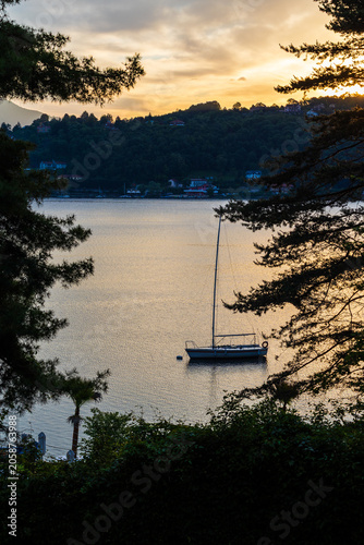 Small sailboat moored on the Lago Grande di Avigliana in the morning light at sunrise, Avigliana Nature Park, Susa Valley