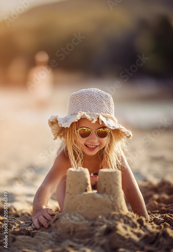 Smiling Blonde Girl Building Sandcastle at Beach During Summer Vacation