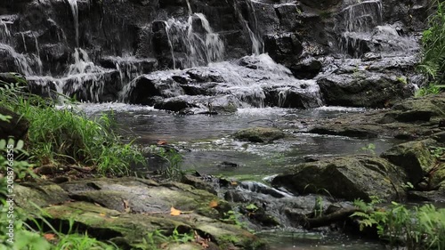 The video background features a natural landscape of a waterfall in a lush forest. Sam Lan Waterfall in Saraburi National Park boasts beautiful flowing water surrounded by diverse flora.