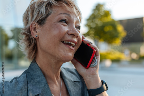 Happy businesswoman talking smartphone outdoors