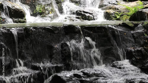 The video background features a natural landscape of a waterfall in a lush forest. Sam Lan Waterfall in Saraburi National Park boasts beautiful flowing water surrounded by diverse flora.