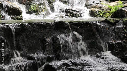The video background features a natural landscape of a waterfall in a lush forest. Sam Lan Waterfall in Saraburi National Park boasts beautiful flowing water surrounded by diverse flora.