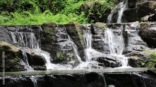 The video background features a natural landscape of a waterfall in a lush forest. Sam Lan Waterfall in Saraburi National Park boasts beautiful flowing water surrounded by diverse flora.