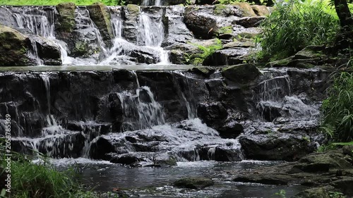 The video background features a natural landscape of a waterfall in a lush forest. Sam Lan Waterfall in Saraburi National Park boasts beautiful flowing water surrounded by diverse flora.