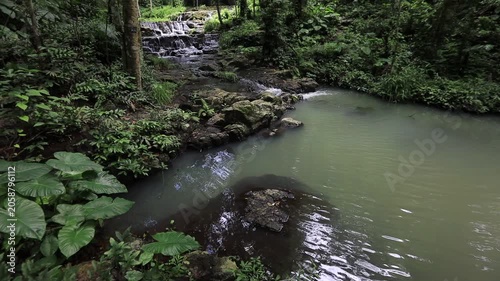 The video background features a natural landscape of a waterfall in a lush forest. Sam Lan Waterfall in Saraburi National Park boasts beautiful flowing water surrounded by diverse flora.