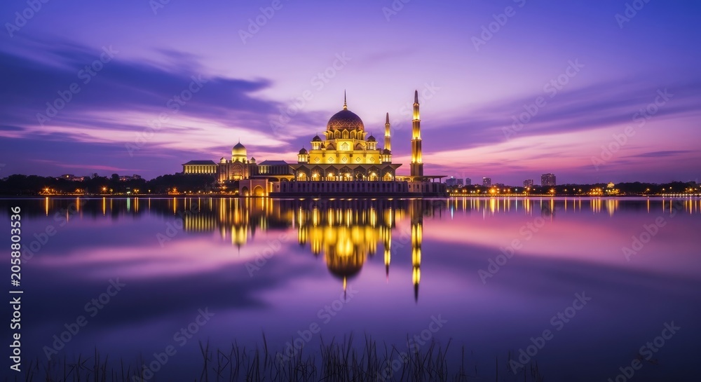 Obraz premium Putra mosque illuminated at dusk with reflection in lake