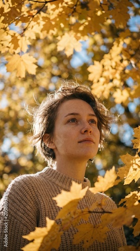 Young woman standing outdoors surrounded by vibrant yellow autumn maple leaves in park