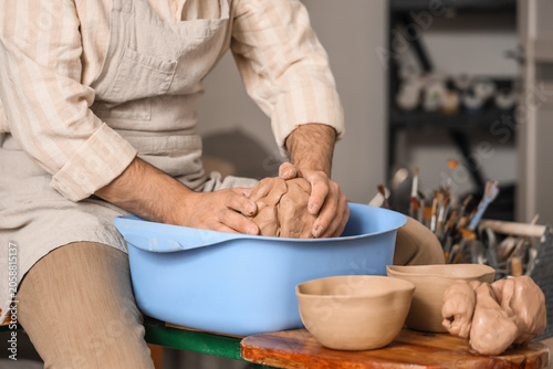 Canvas Print Potter kneading clay in blue basin for pottery crafting and ceramic art creation