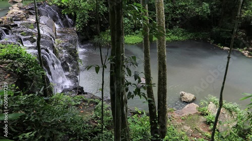 The video background features a natural landscape of a waterfall in a lush forest. Sam Lan Waterfall in Saraburi National Park boasts beautiful flowing water surrounded by diverse flora.