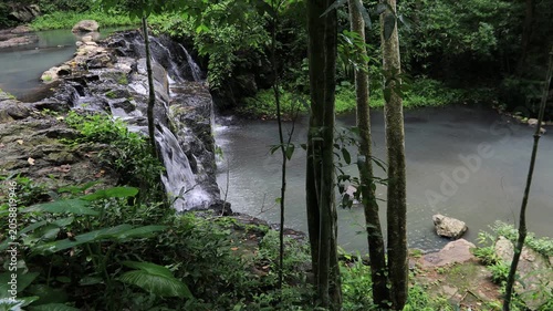 The video background features a natural landscape of a waterfall in a lush forest. Sam Lan Waterfall in Saraburi National Park boasts beautiful flowing water surrounded by diverse flora.