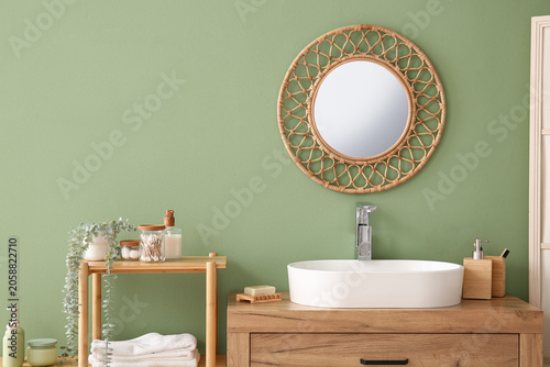 Photos Modern bathroom interior with rattan mirror, wooden vanity, white sink, and eco-