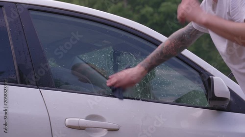 A man washes the car windows with a cloth before applying an anti-rain coating.
