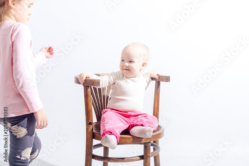 Obraz na plátně Pretty little sisters are playing in the photo studio with white background