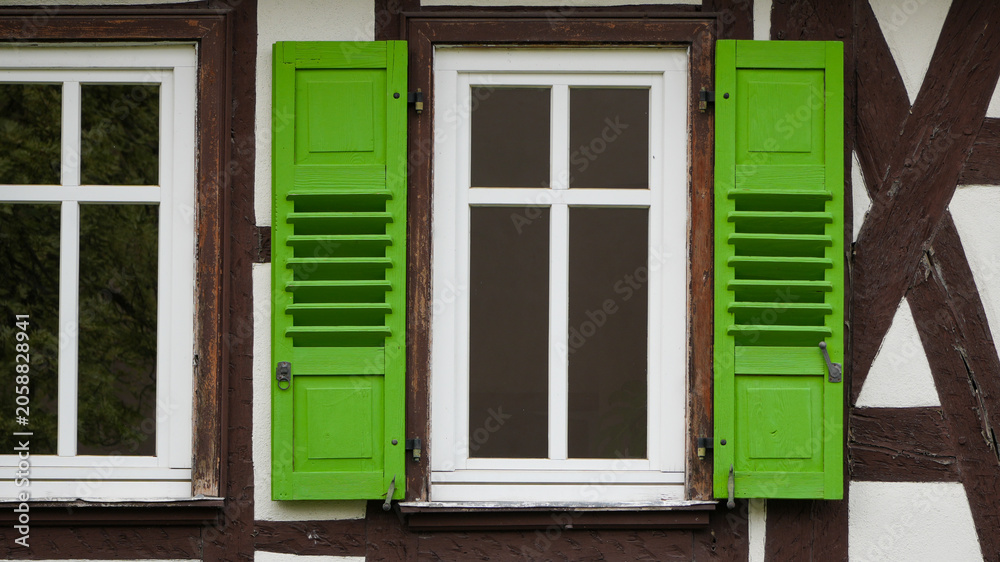 Fototapeta premium traditional half timbered house facade with window and bright green shutters
