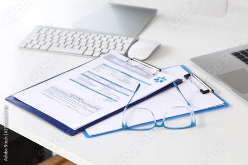 Photos Health insurance form with eyeglasses and laptop on white desk, medical coverage
