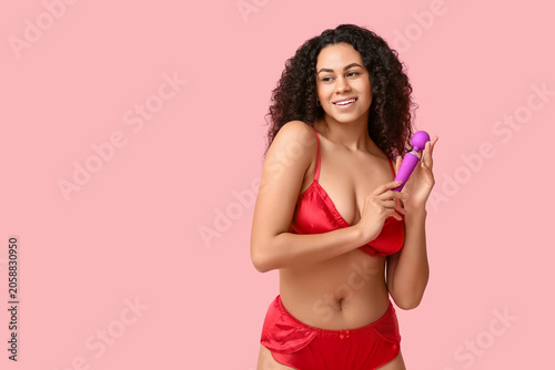 Foto Smiling young woman in red lingerie holding purple vibrator, female pleasure and