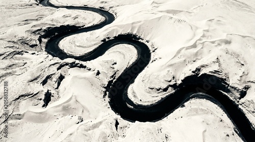 Aerial view of a winding asphalt road through a stark white desert landscape.