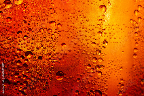 Картината върху платно A close-up image of condensed water droplets on a cold glass surface against a warm golden background; Kola Macro beverage texture,A macro photograph capturing intricate water droplets