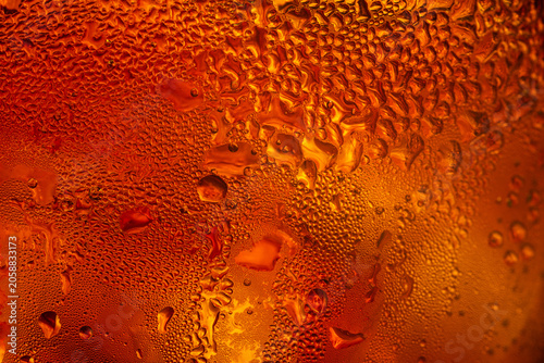 A close-up image of condensed water droplets on a cold glass surface against a warm golden background; Kola Macro beverage texture,A macro photograph capturing intricate water droplets.