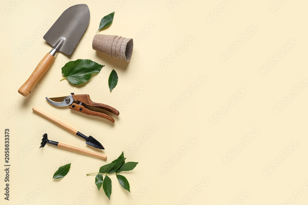 Naklejka premium Gardening tools with shovel, pruner and peat pot on beige background. Top view