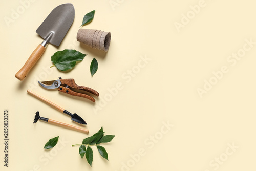 Gardening tools with shovel, pruner and peat pot on beige background. Top view