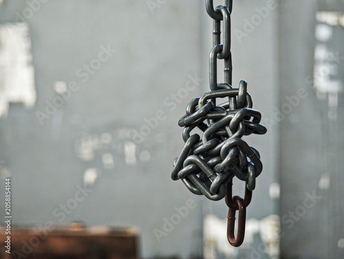 Cuadro en lienzo Close up of a tangled and messy metal chain hanging with a rusty link at the bottom, conceptualizing complicated problems, hardship, and security breakdown