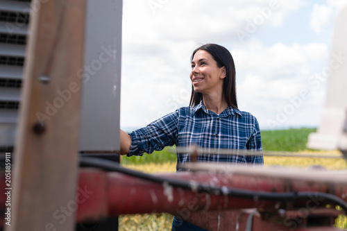 фотографія Female farmer checking agriculture machinery in field