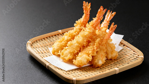 Shrimp tempura served on a wooden plate with white paper  