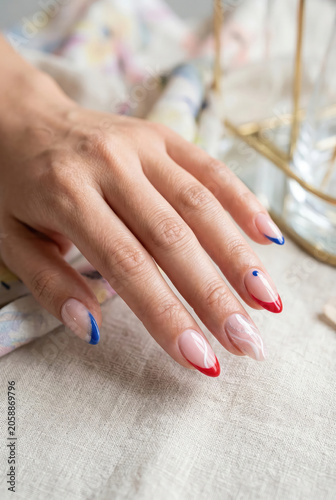 minimal patriotic manicure with red blue French tips and white swirl on almond nails
