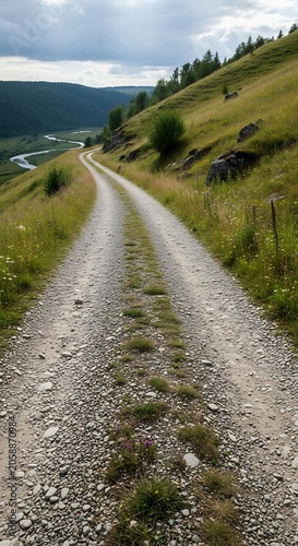Winding gravel road through lush green grassy hills leading to a distant valley