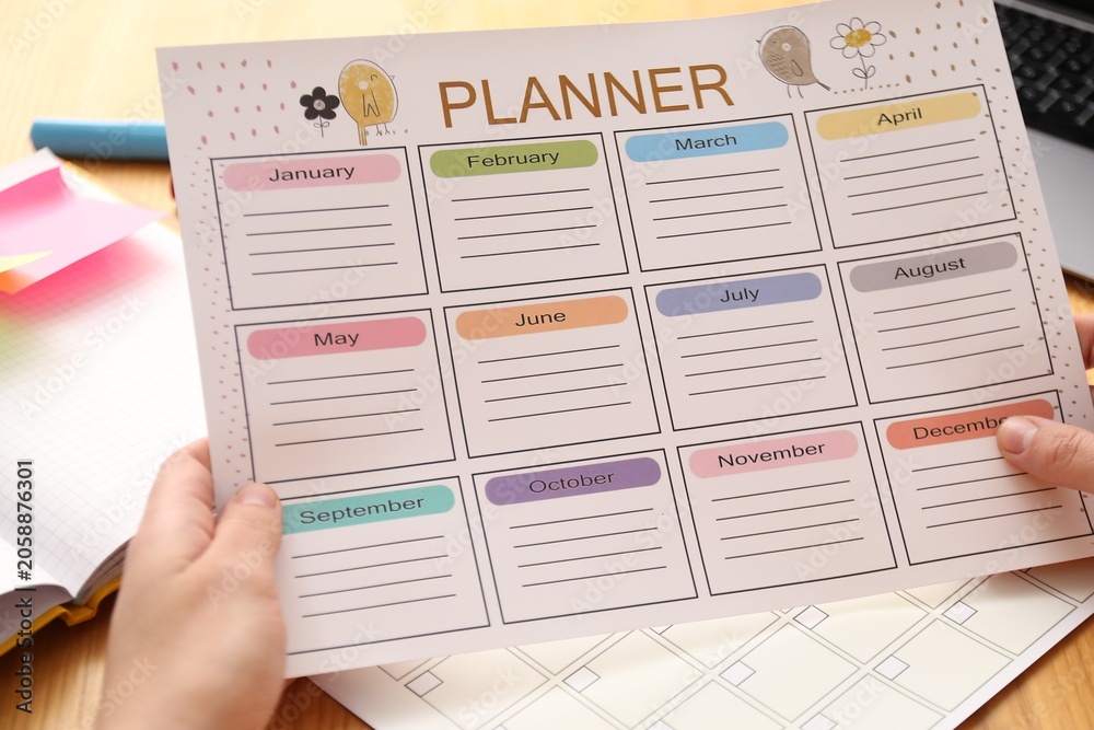 Obraz premium Woman using planner at wooden table, closeup