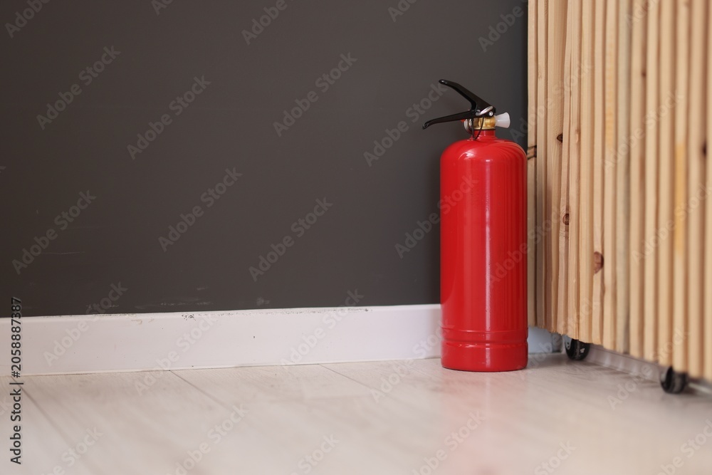 Obraz premium One red fire extinguisher on floor indoors, space for text