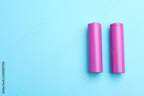 Fotografía Two alkaline batteries on light blue background, flat lay
