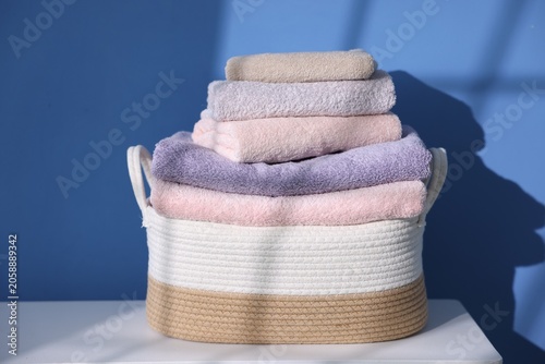 Canvastavla Many clean towels in laundry basket on white table near blue wall, closeup