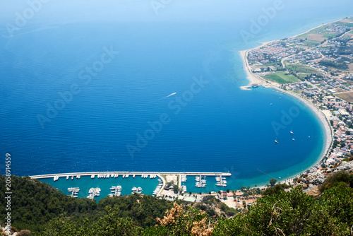 High angle panoramic vista of a scenic crescent shaped sea bay and coastal harbor town