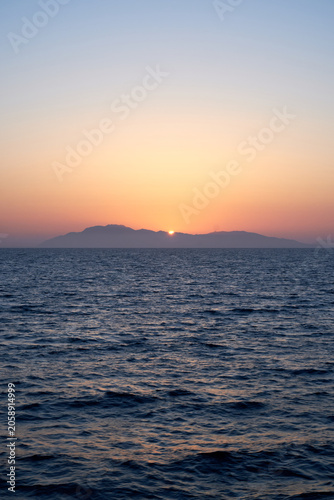 Vertical scenic landscape of a serene evening sunset over calm dark ocean waves