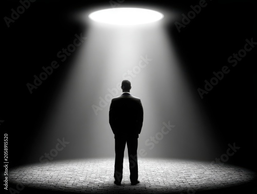 Man standing under spotlight in dark environment  