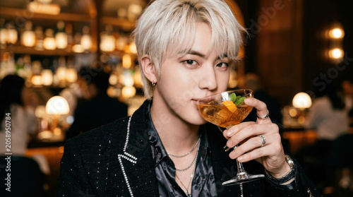 Young Asian Man with Silver Hair Sipping a Cocktail