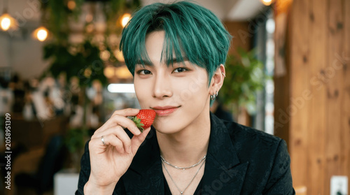 Handsome Young Asian Man with Green Hair Holding a Fresh Strawberry