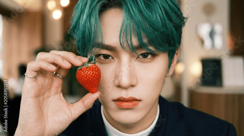 Handsome Young Asian Man with Green Hair Holding a Fresh Strawberry