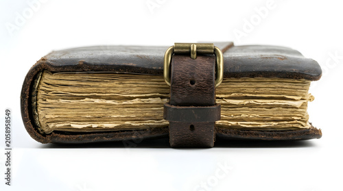 An old, leather-bound book with a buckle closure sits closed, its aged pages hinting at stories untold and knowledge preserved.