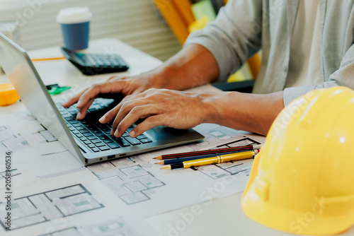 Photography Dedicated civil designer verifying safety metrics on laptop display next to miniature model