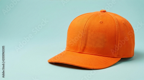 Obraz na płótnie Blank orange baseball cap isolated on a light blue background with ample copy space