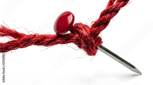 A sharp needle pierces a red rope, forming a knot that signifies a delicate connection or a point of tension.